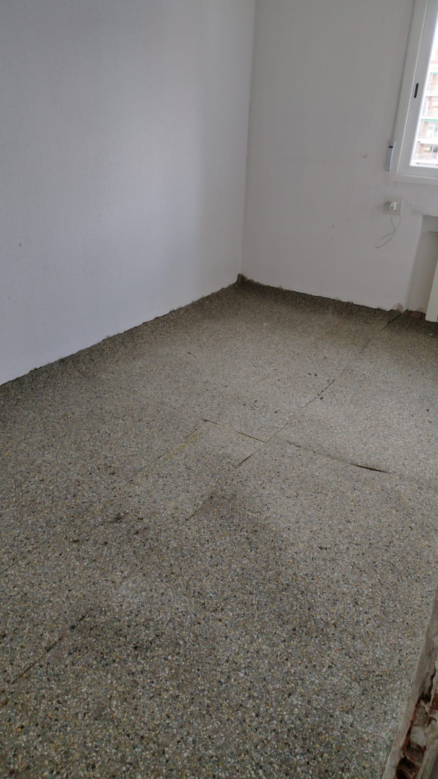 Una habitación vacía con suelo alfombrado y paredes blancas.