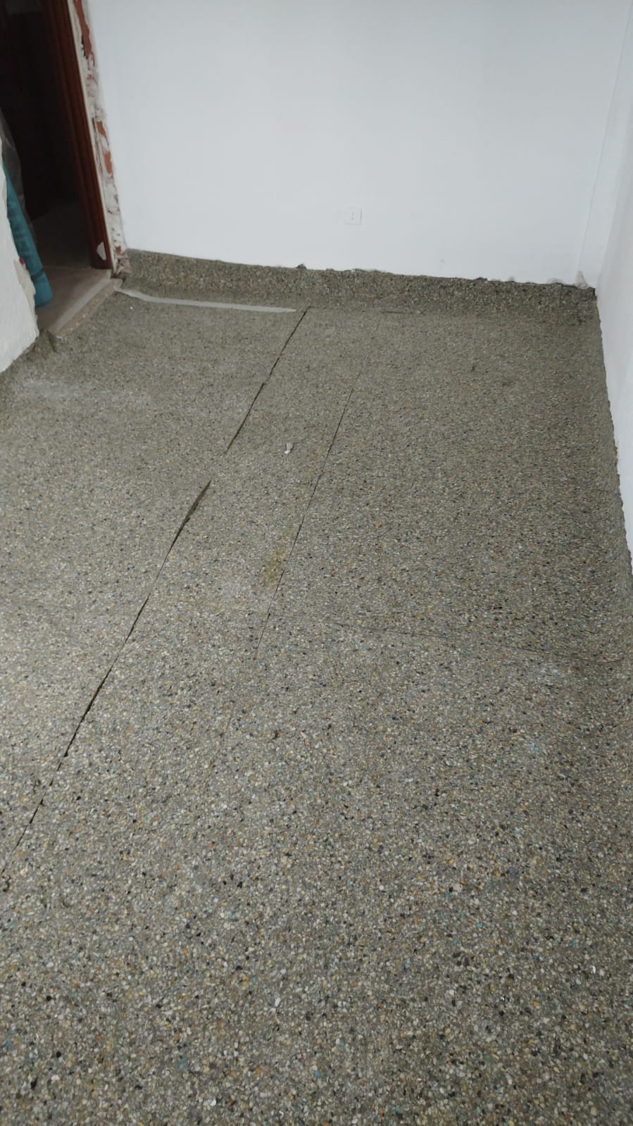 Una habitación con piso de concreto y una pared blanca.