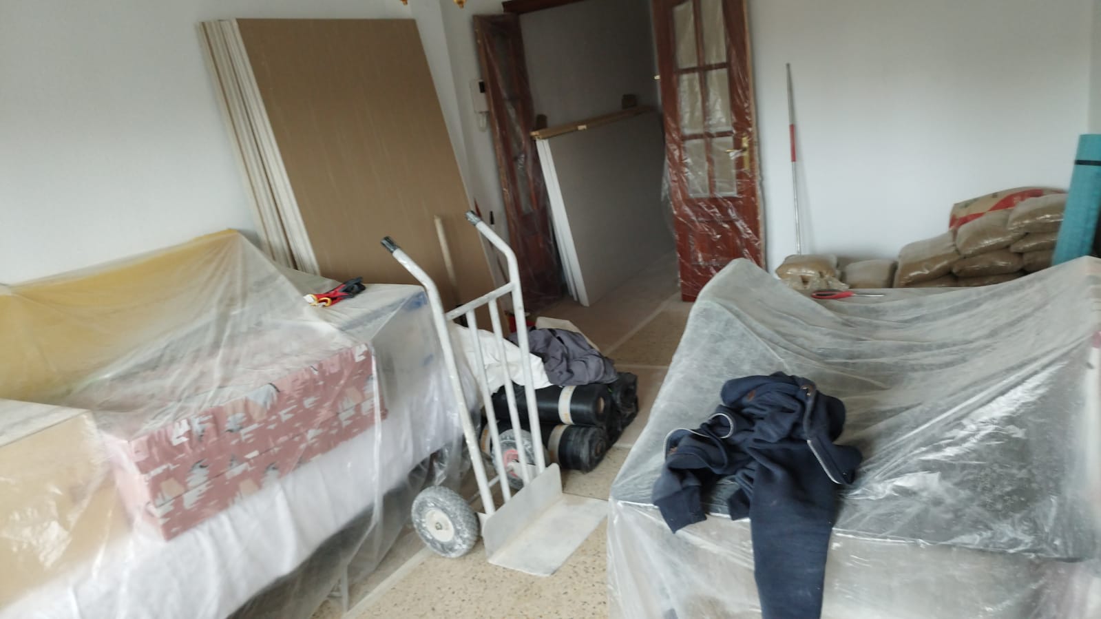 Una habitación con un sofá y un carrito cubierto de plástico