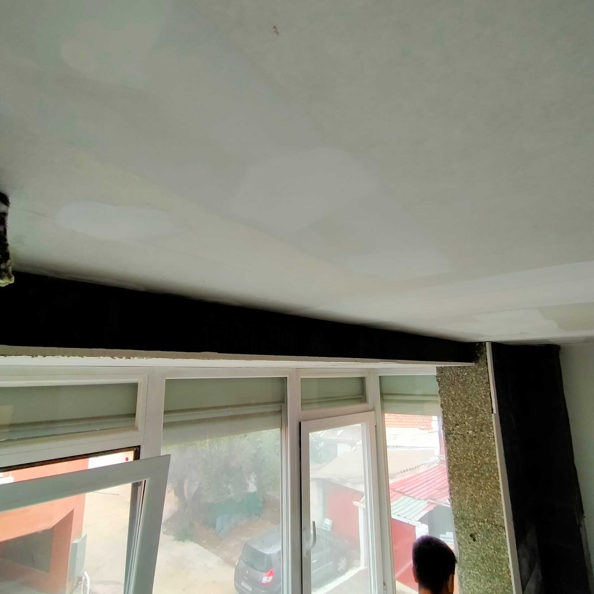 Un hombre está parado frente a una ventana en una habitación.