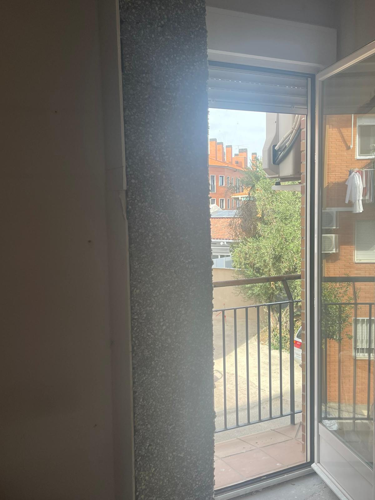 Una habitación con balcón y puerta corredera de cristal