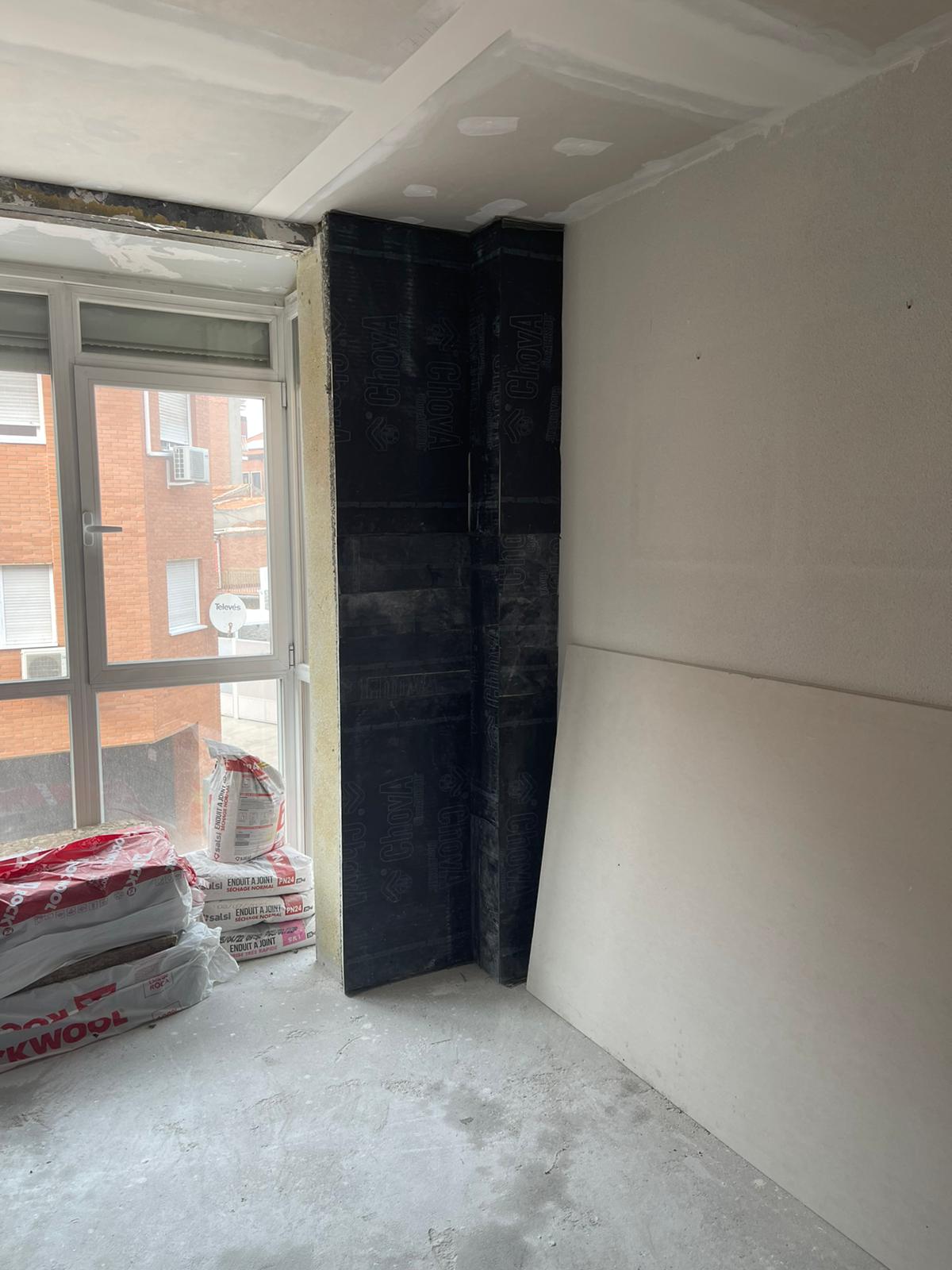 Una habitación con una ventana y una pila de bolsas de aislamiento en el suelo.