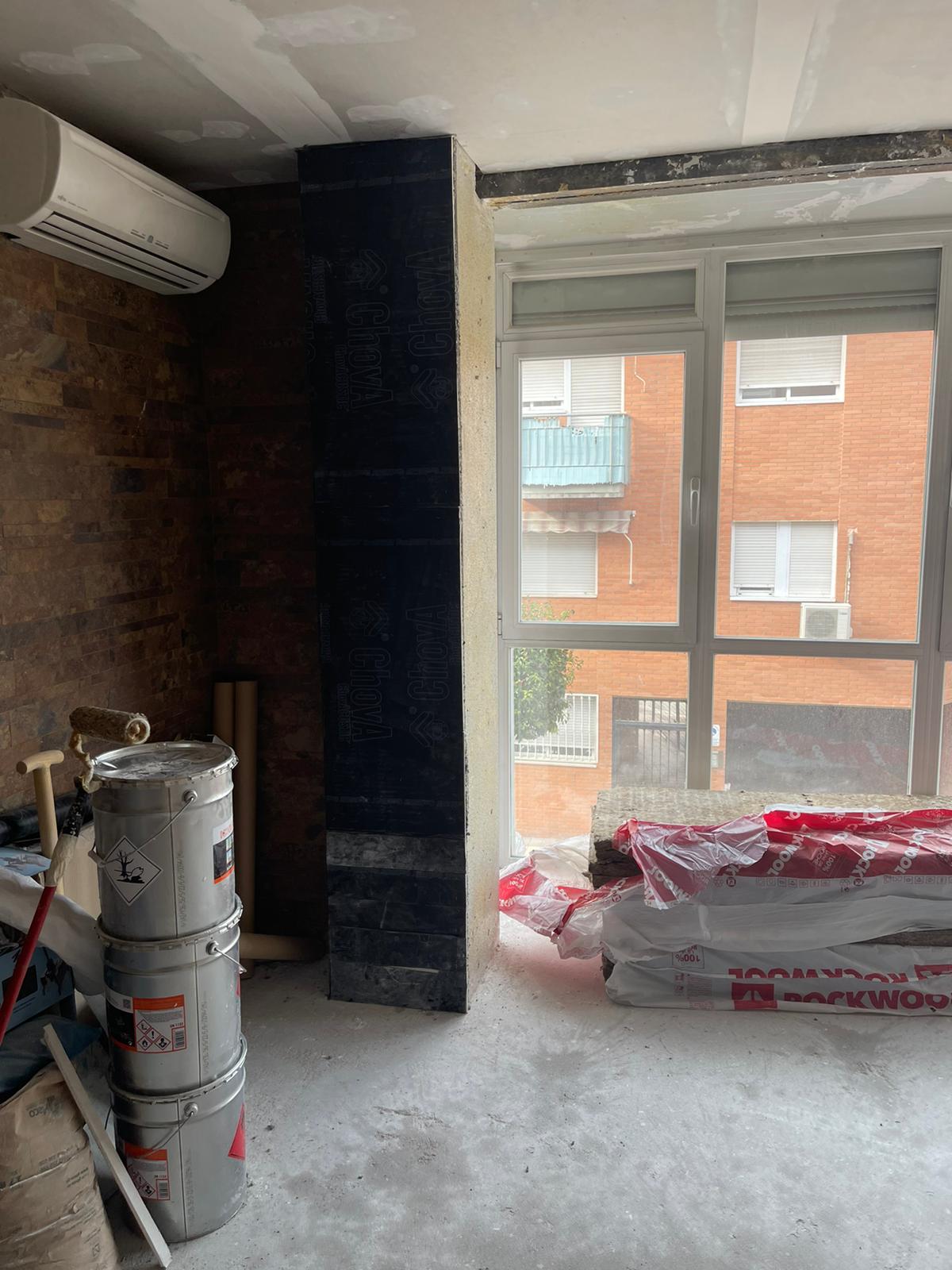 Una habitación con muchas ventanas y una pila de cubos en el suelo.