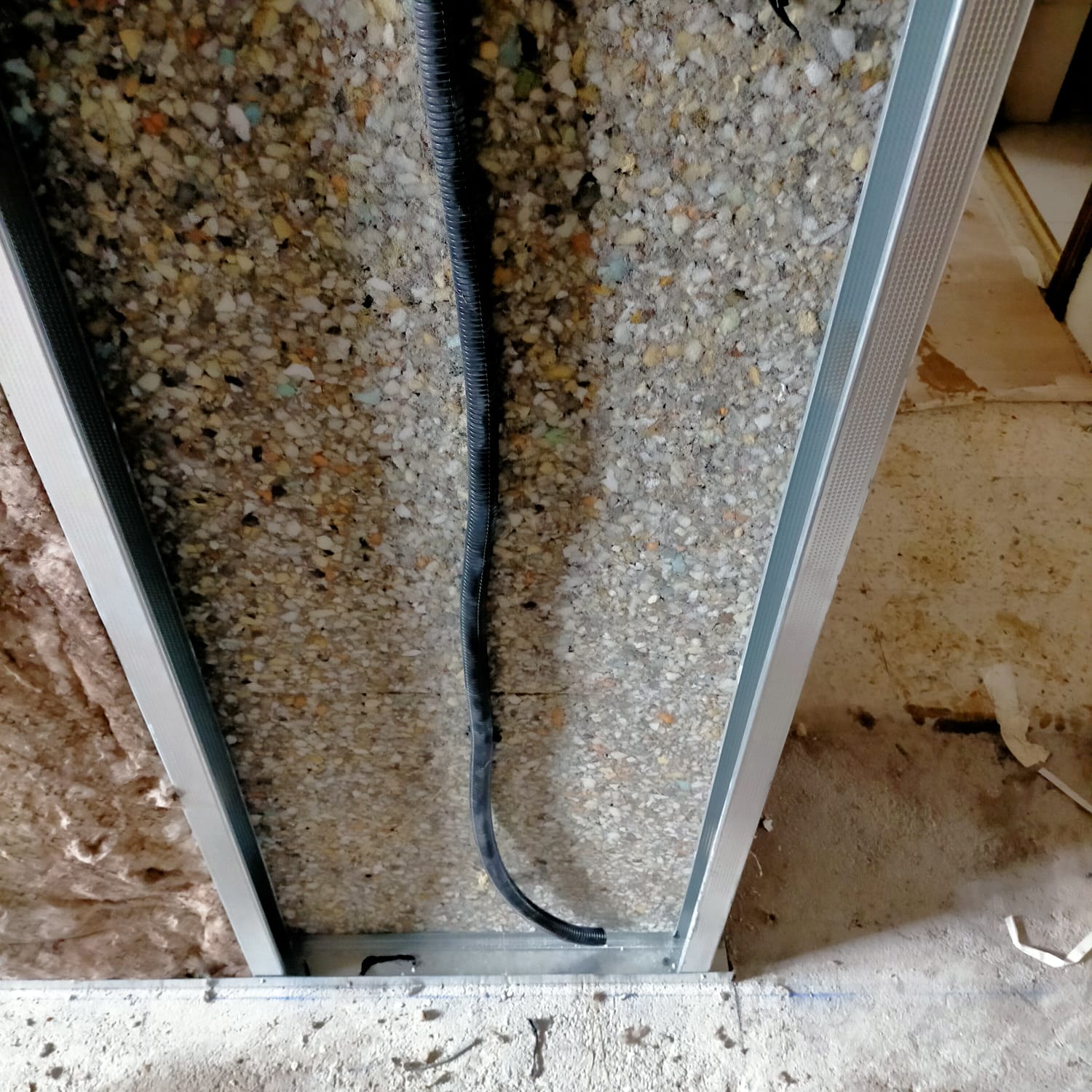 Un cable negro cuelga de un marco de metal en una pared.