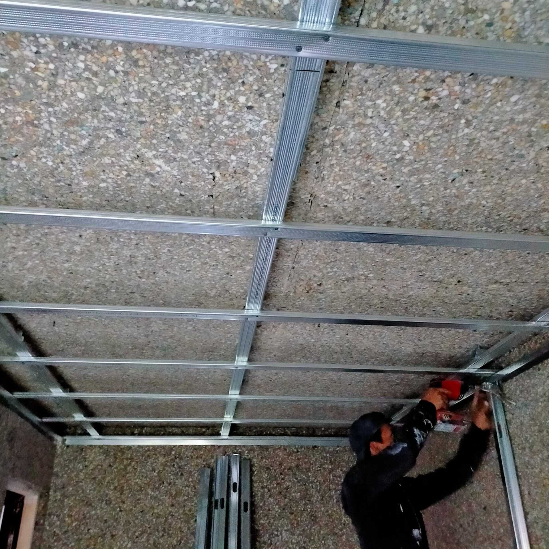 Un hombre está trabajando en el techo con un taladro.