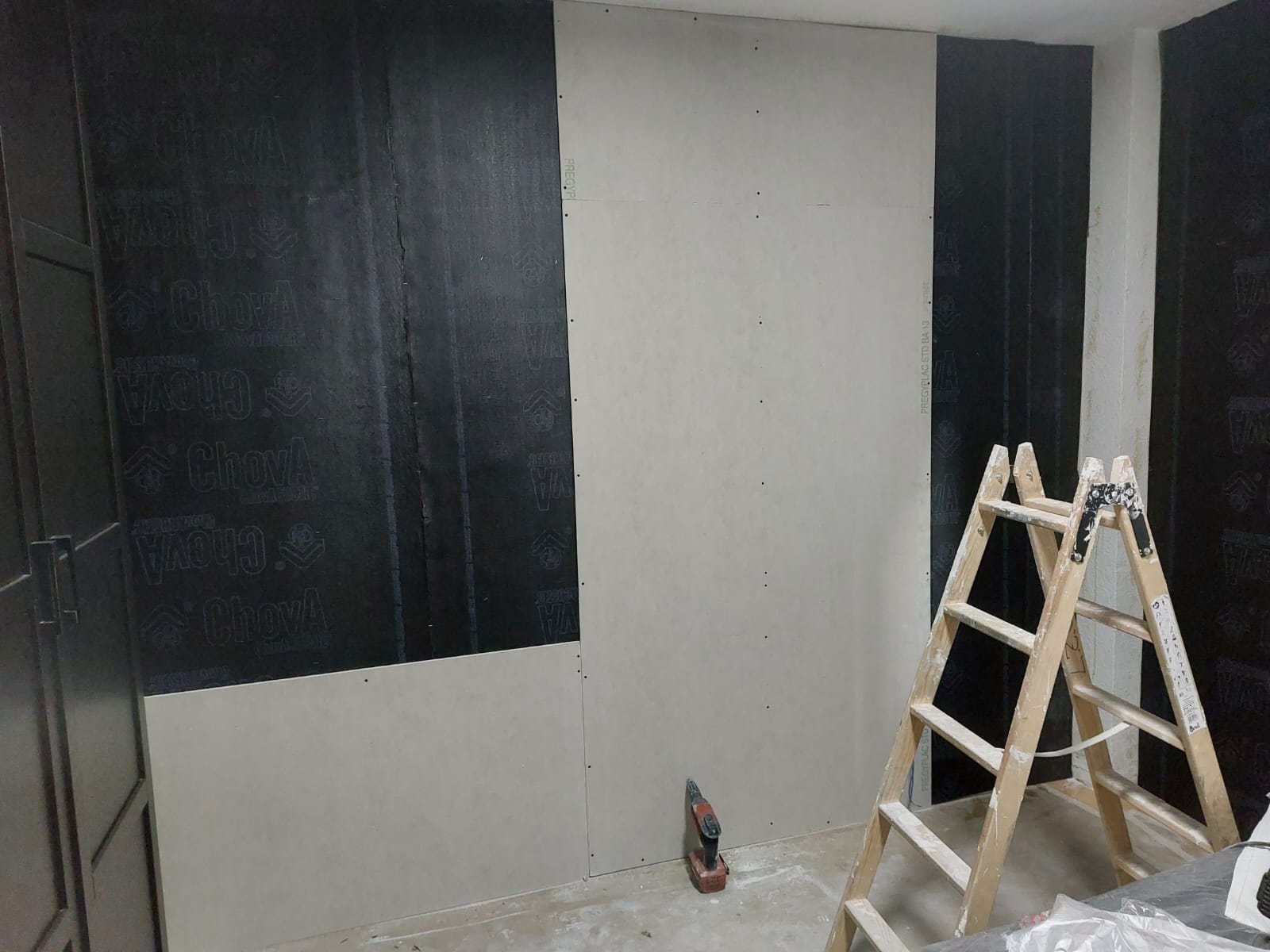 Una habitación con una escalera y una pared negra.