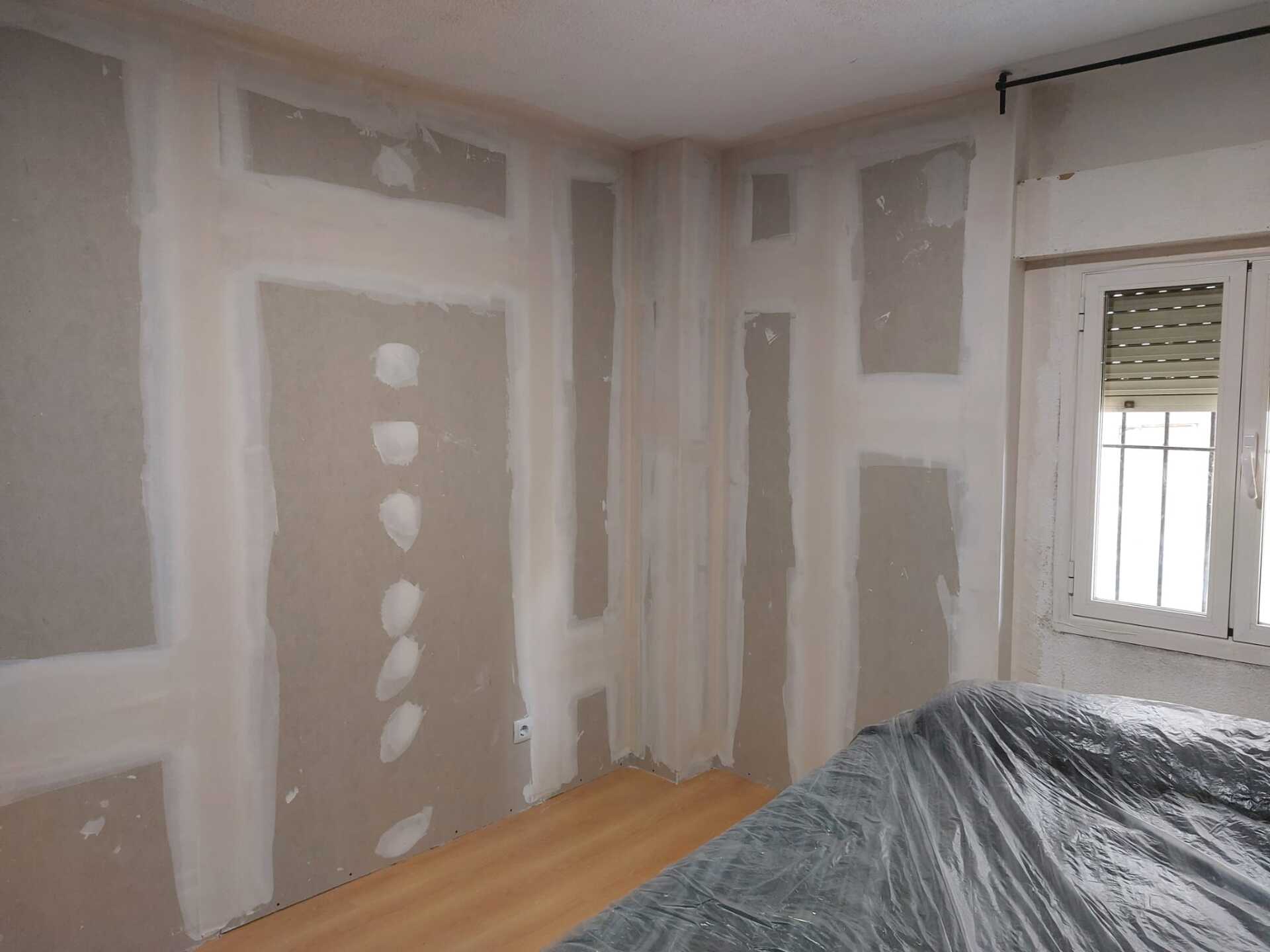 Una habitación con una cama y una ventana cubierta de plástico