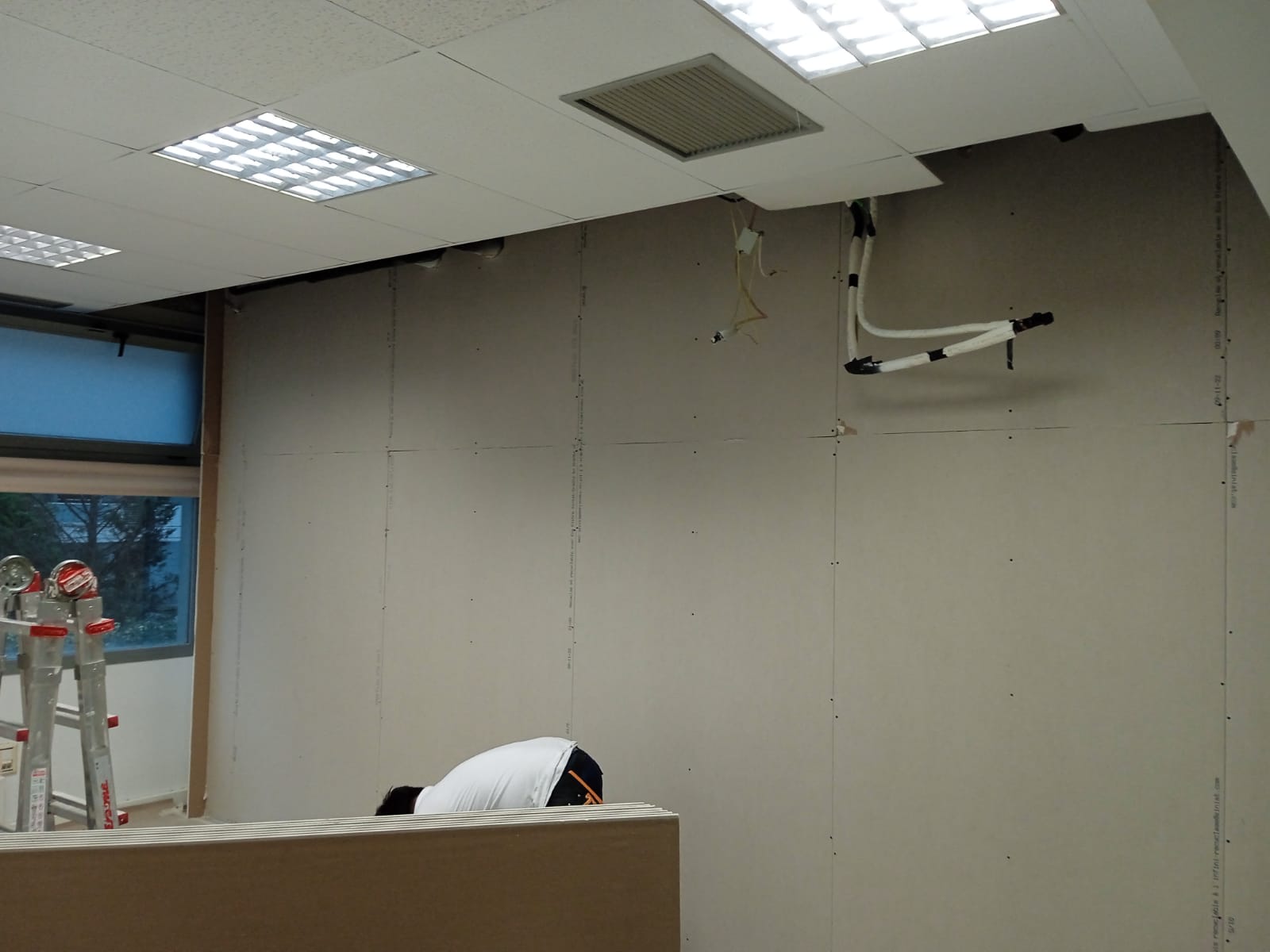 Un hombre está arrodillado en una habitación con una escalera al fondo.