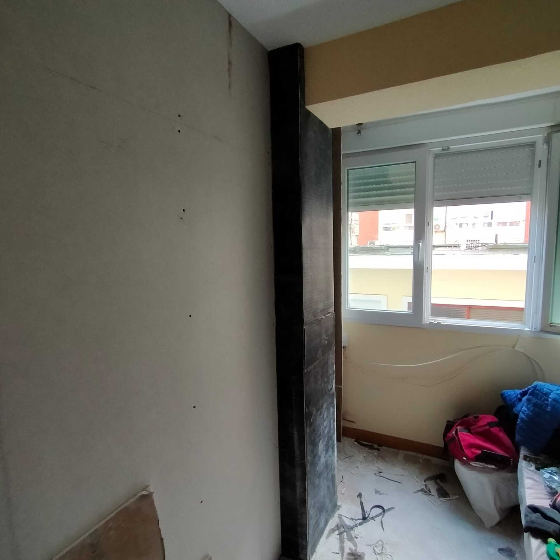 Una esquina de una habitación con una ventana y una puerta