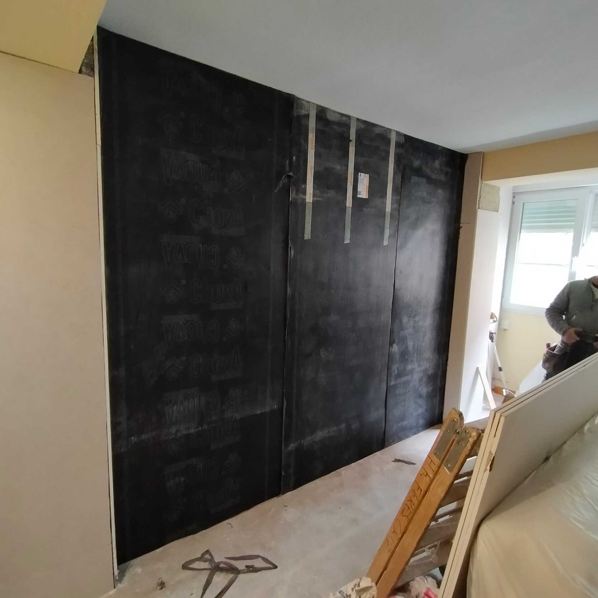 Un hombre está trabajando en una pared de una habitación