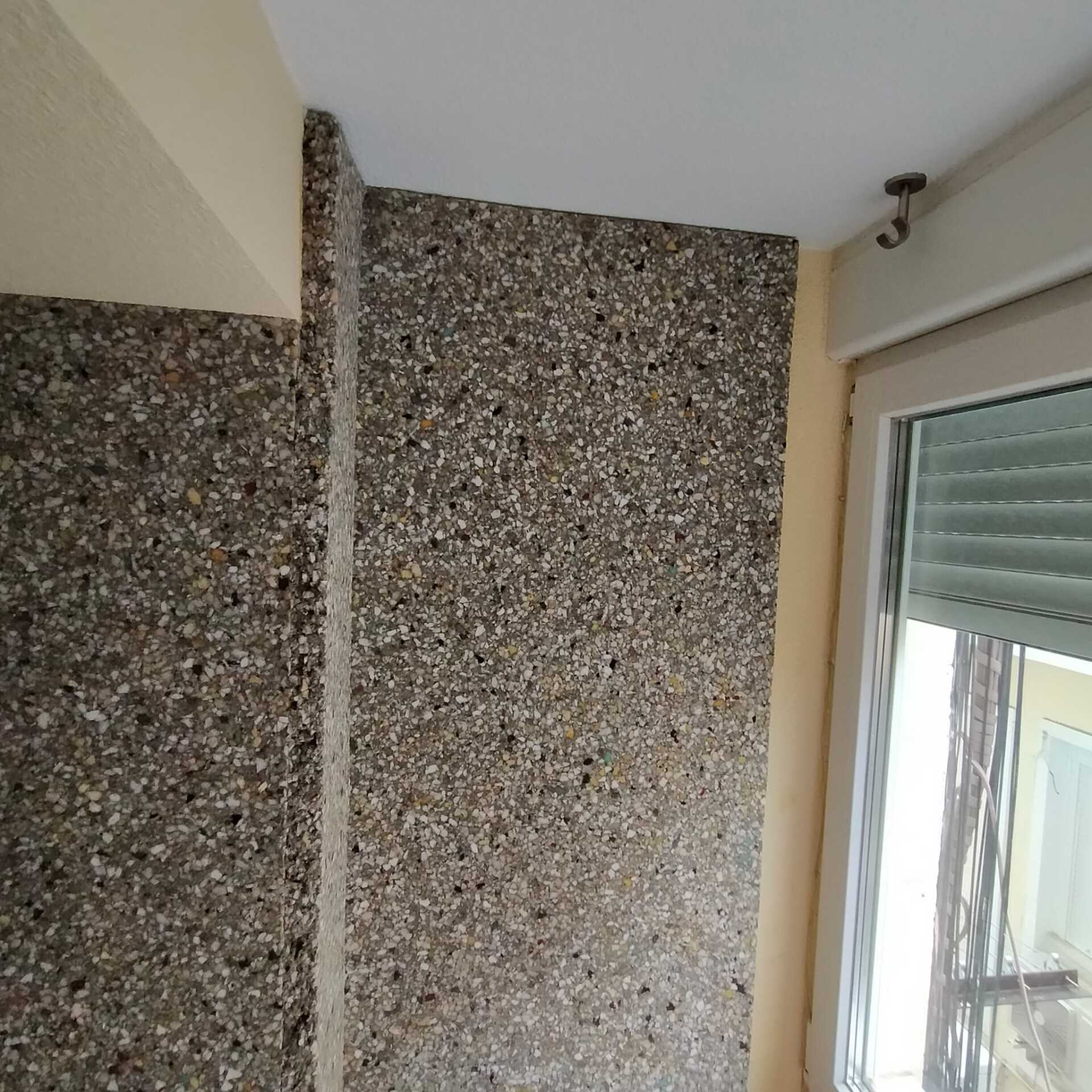 Un rincón de una habitación con una ventana y un muro de piedra.