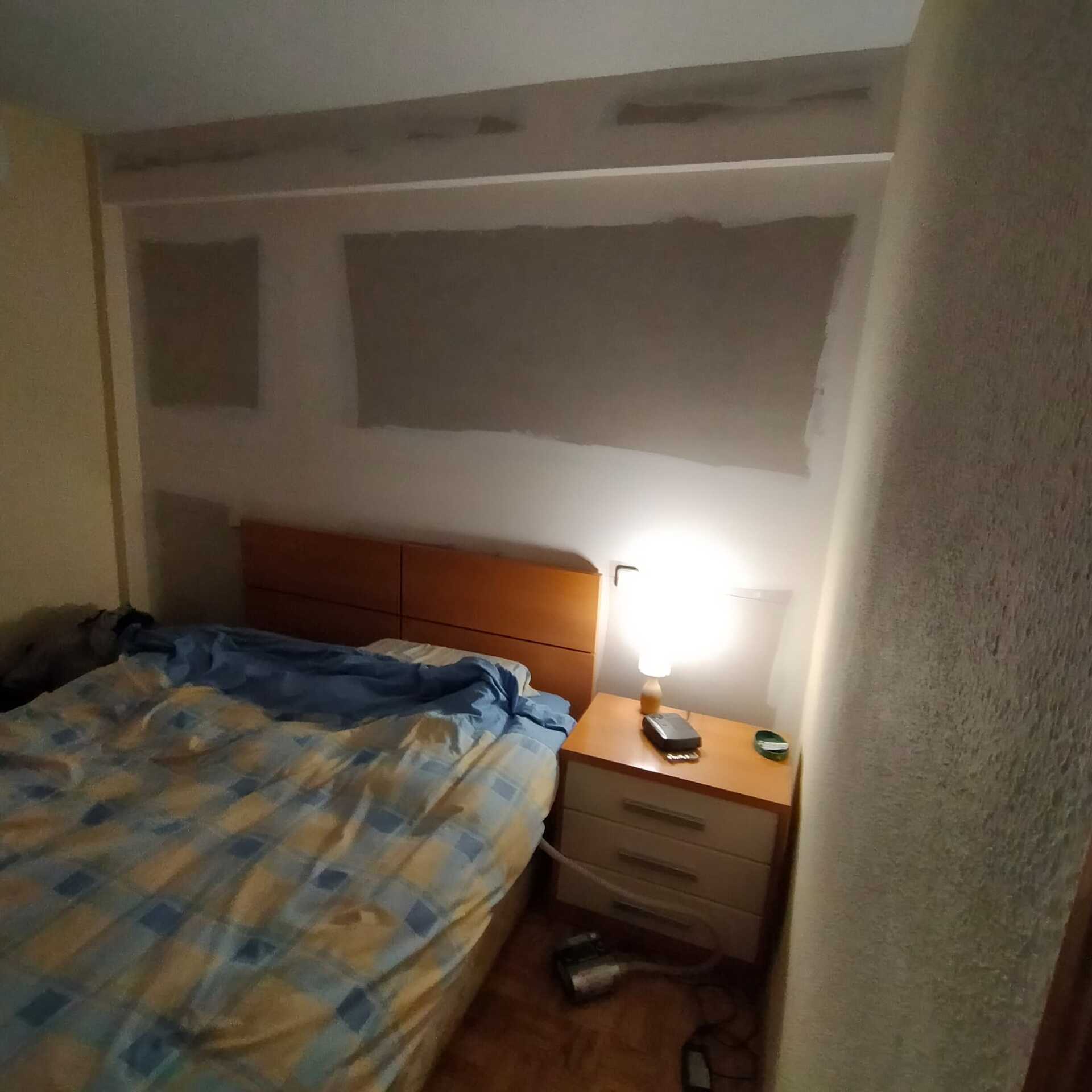 Un dormitorio con una cama y una mesita de noche con una lámpara