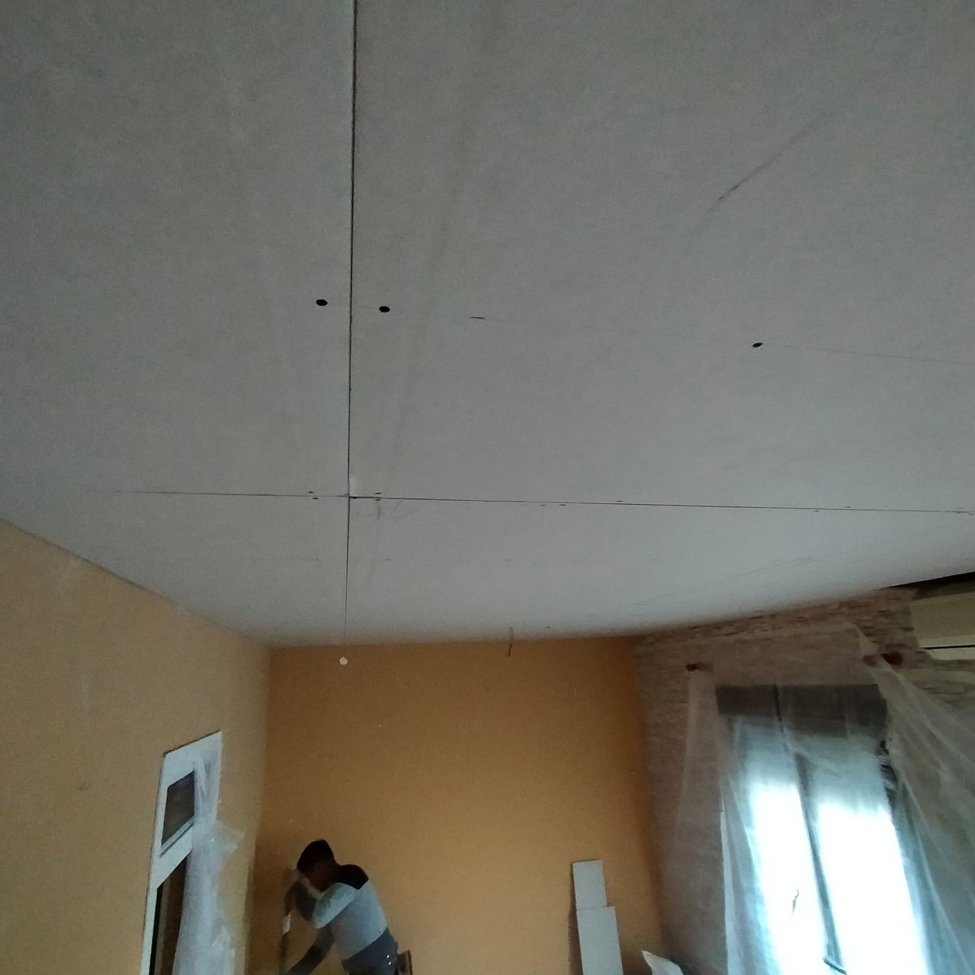 Un hombre está trabajando en el techo de una habitación