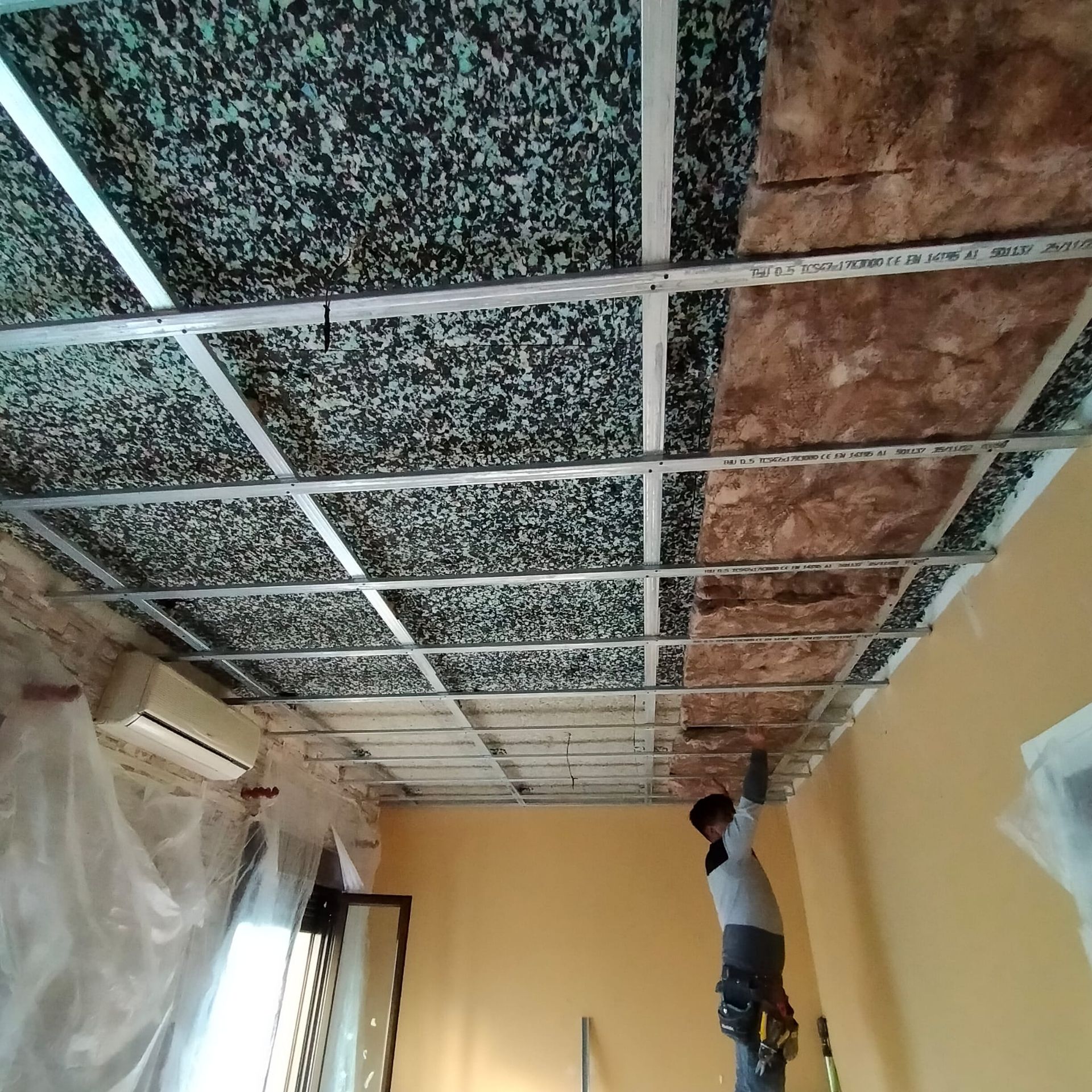 Un hombre está trabajando en el techo de una habitación