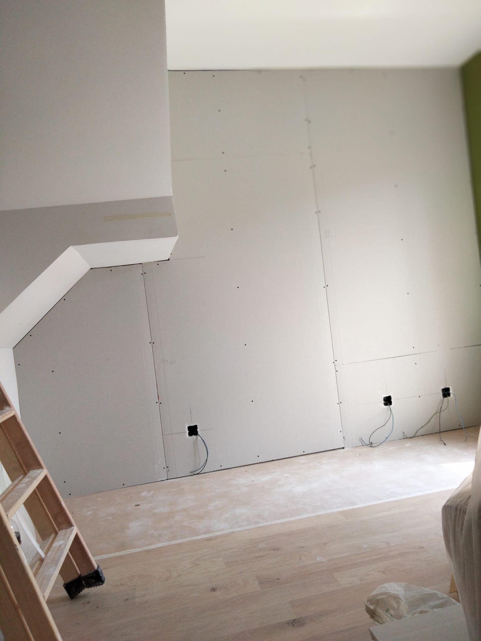 Una habitación con una escalera y una gran pared blanca.