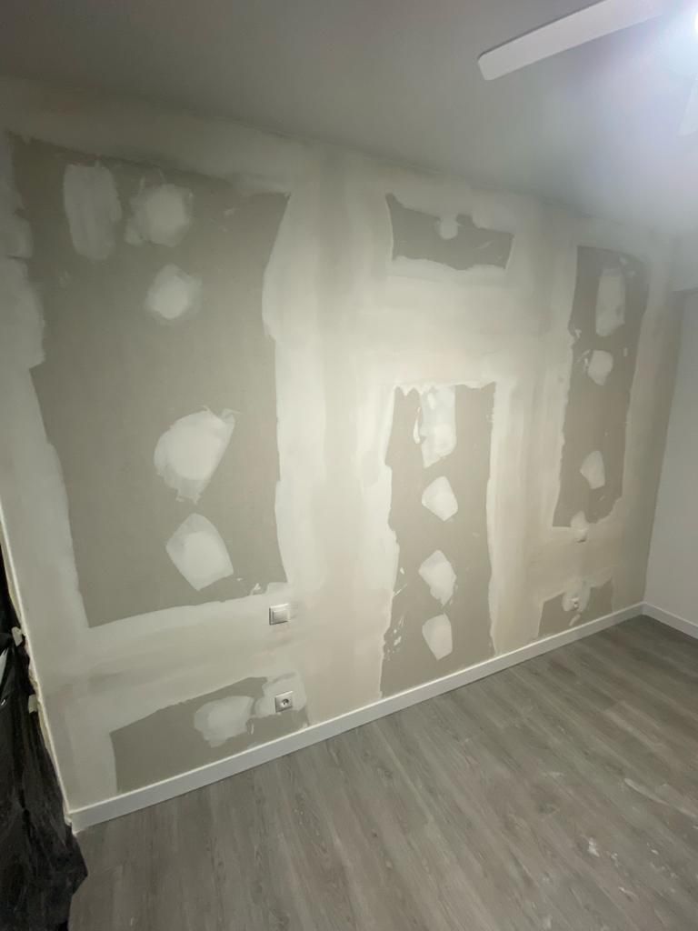 Una habitación con paredes de yeso y piso de madera.