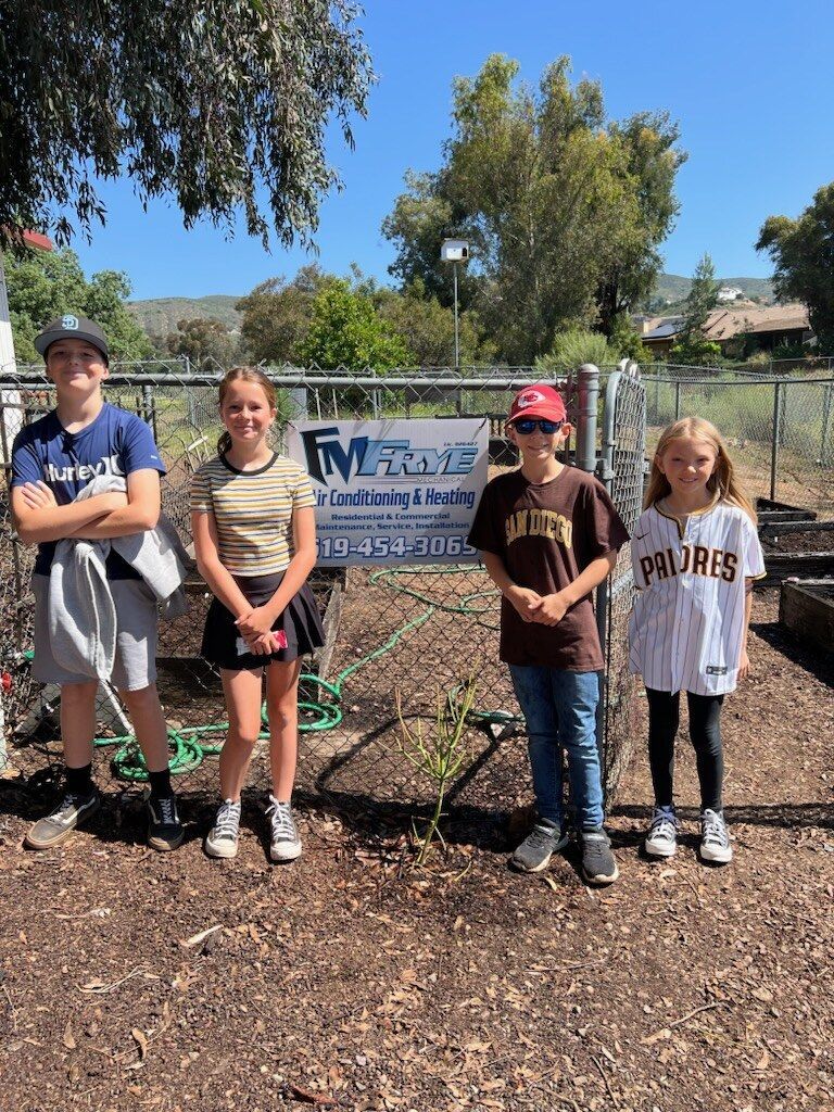 A group of children are standing next to each other in a garden.