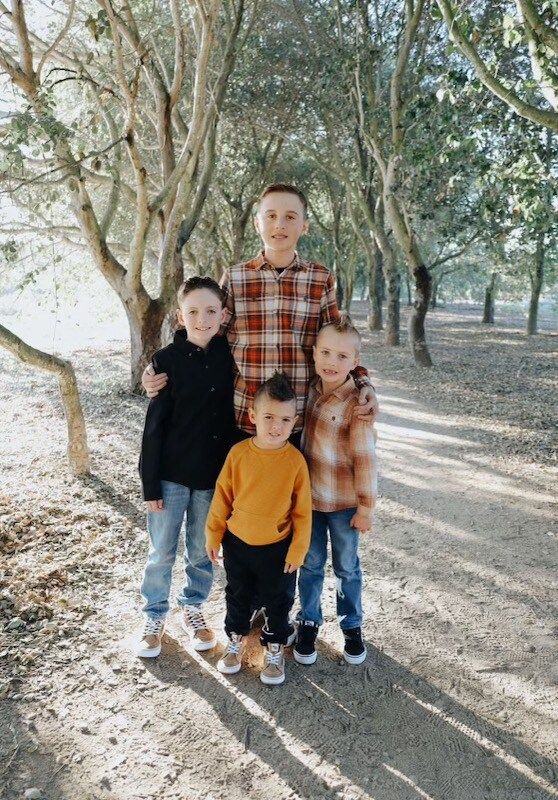 A group of young boys are posing for a picture in a forest.