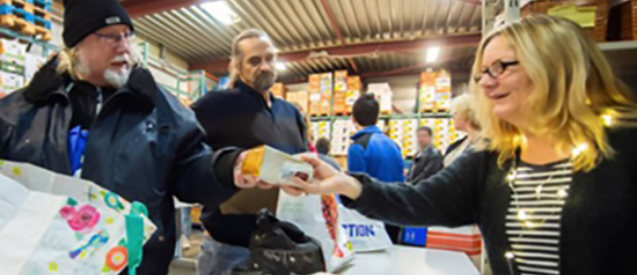 A woman is giving a man a bottle of milk in a warehouse.