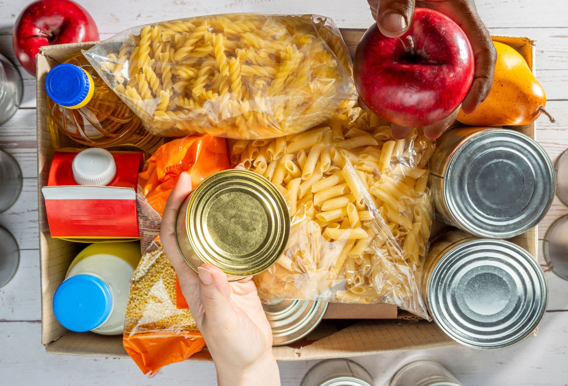 A person is opening a can of food in front of a box of food.