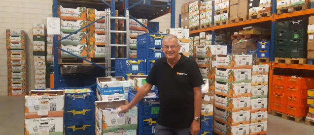 A man is standing in a warehouse filled with lots of boxes.
