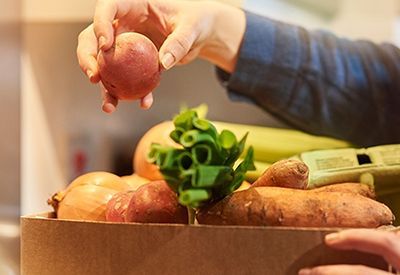 A person is opening a can of food in front of a box of food.