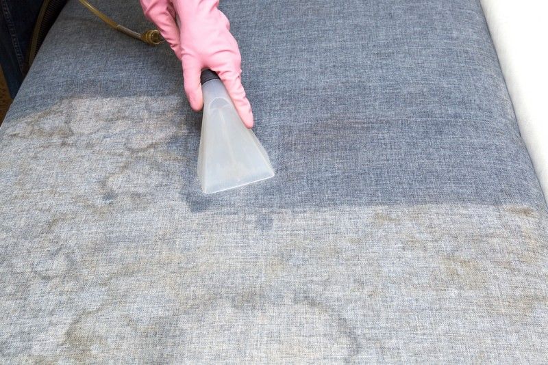 Person in Pink Glove Using Upholstery Cleaner on a Gray Carpet — Mo Property Cleaning in Queanbeyan, ACT