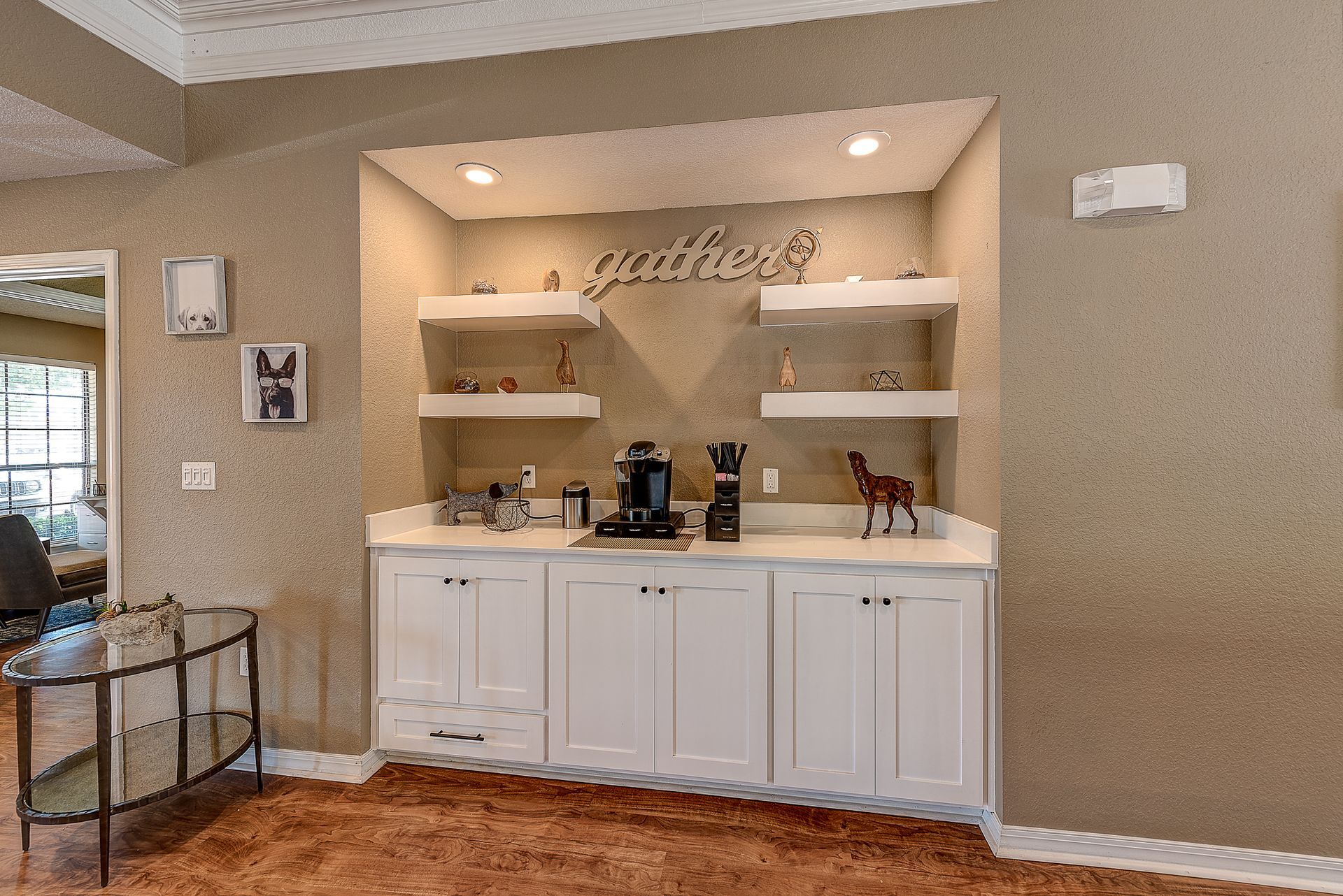 A kitchen with white cabinets , shelves and a coffee maker.