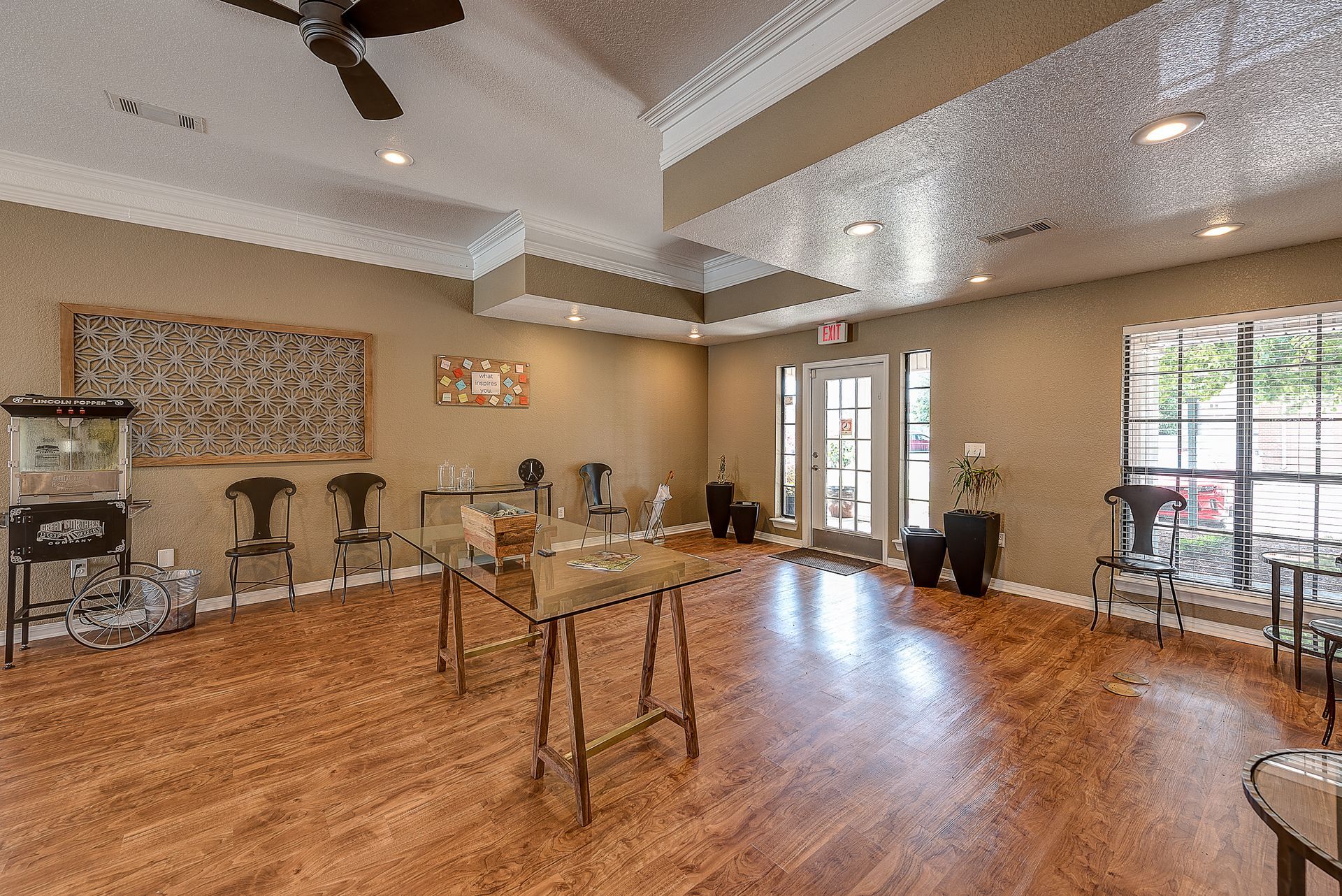 A large room with hardwood floors , tables , chairs and a ceiling fan.