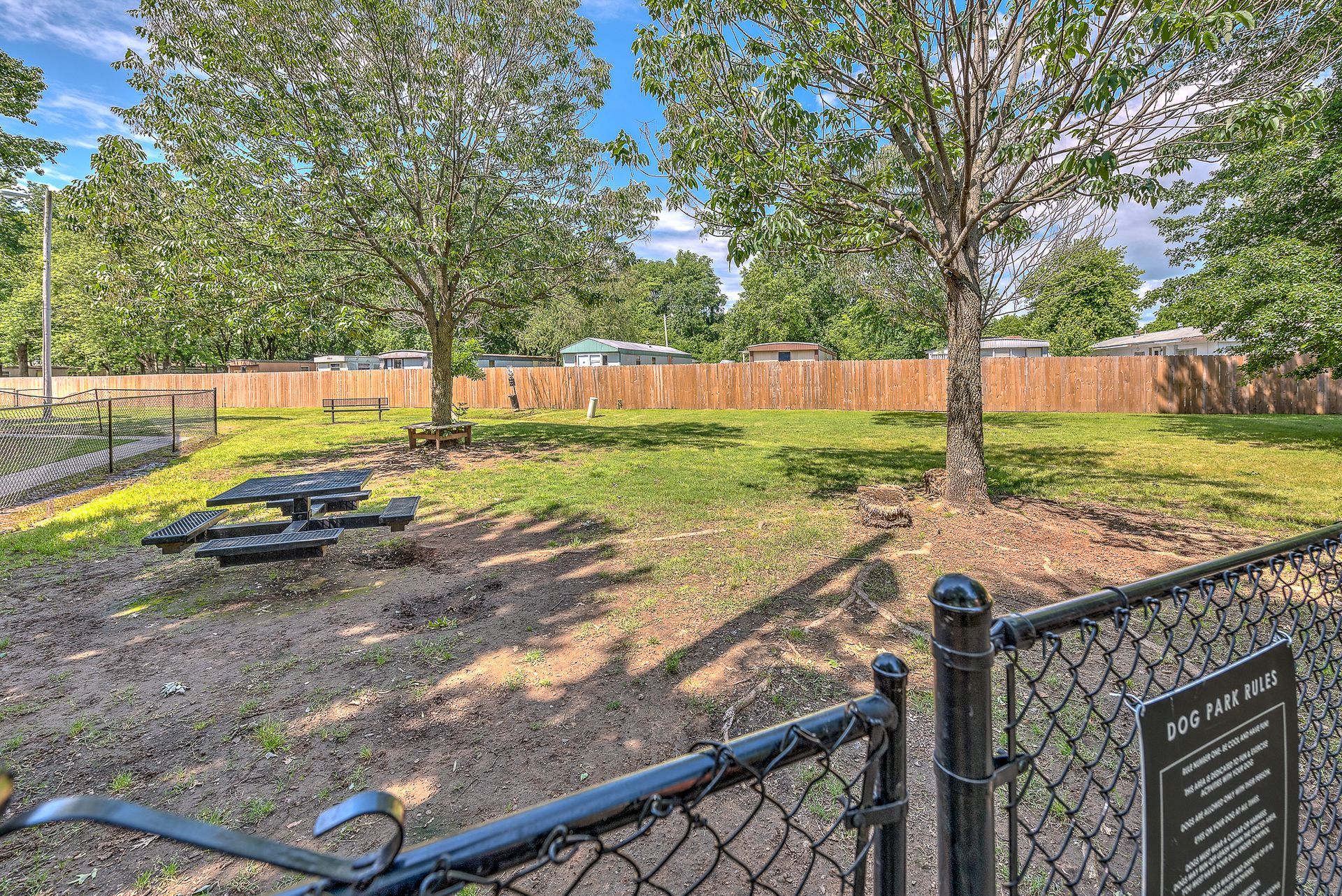 A dog park with a chain link fence and picnic tables.