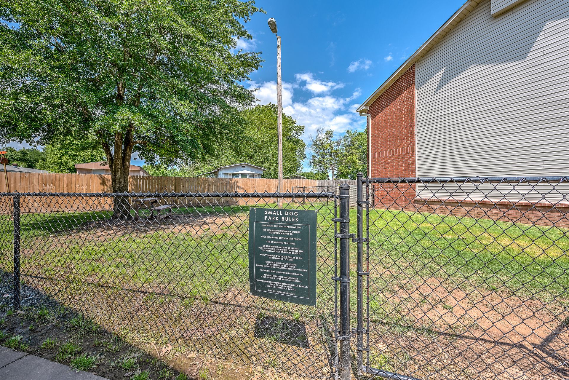 A chain link fence with a sign hanging from it in front of a house.