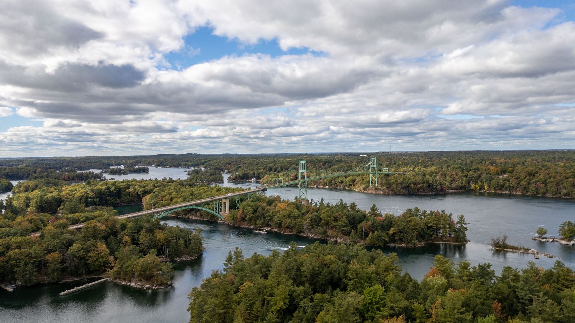 An aerial view of a bridge over a lake surrounded by trees.