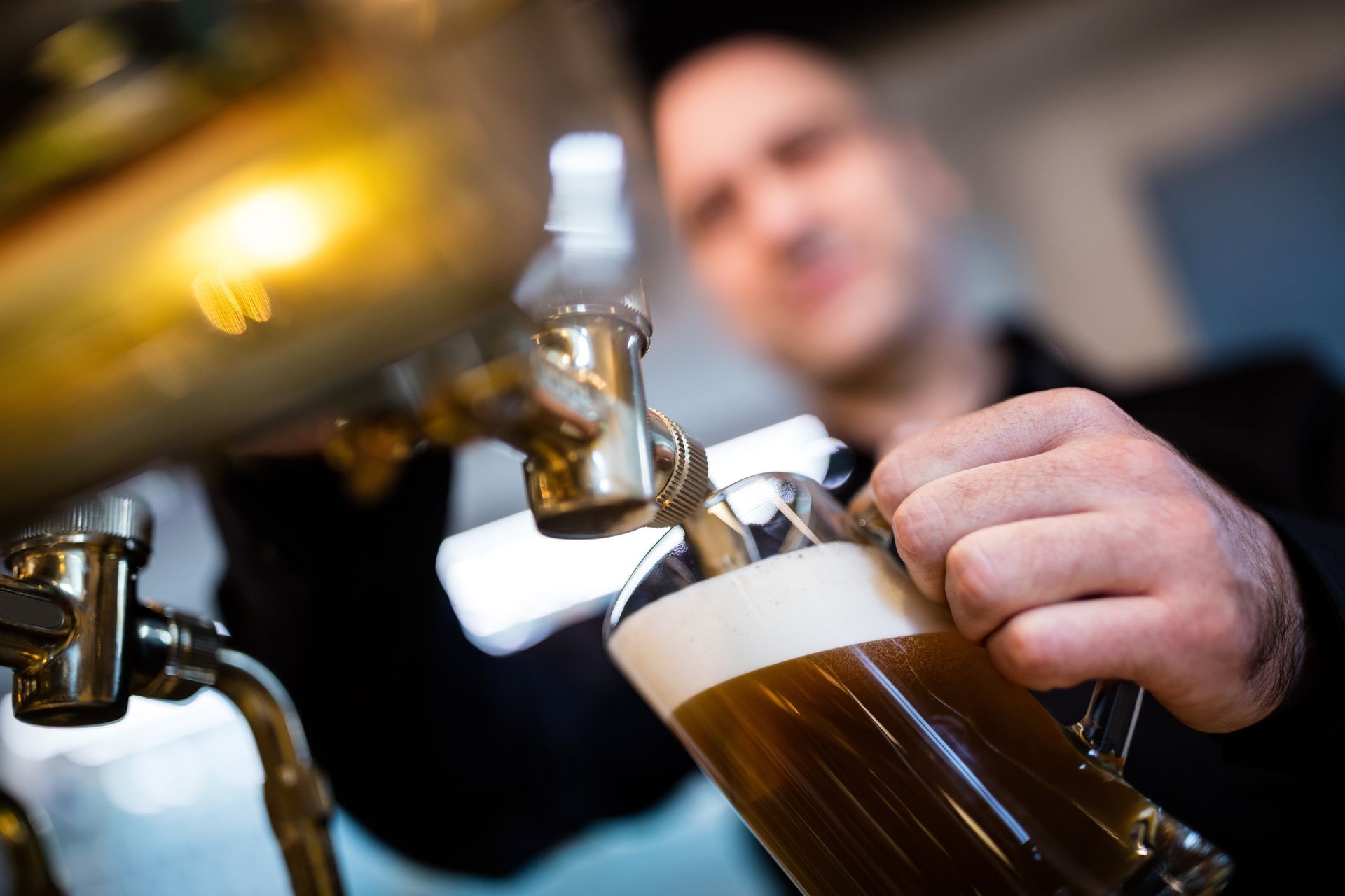 A man is pouring beer into a glass from a tap.
