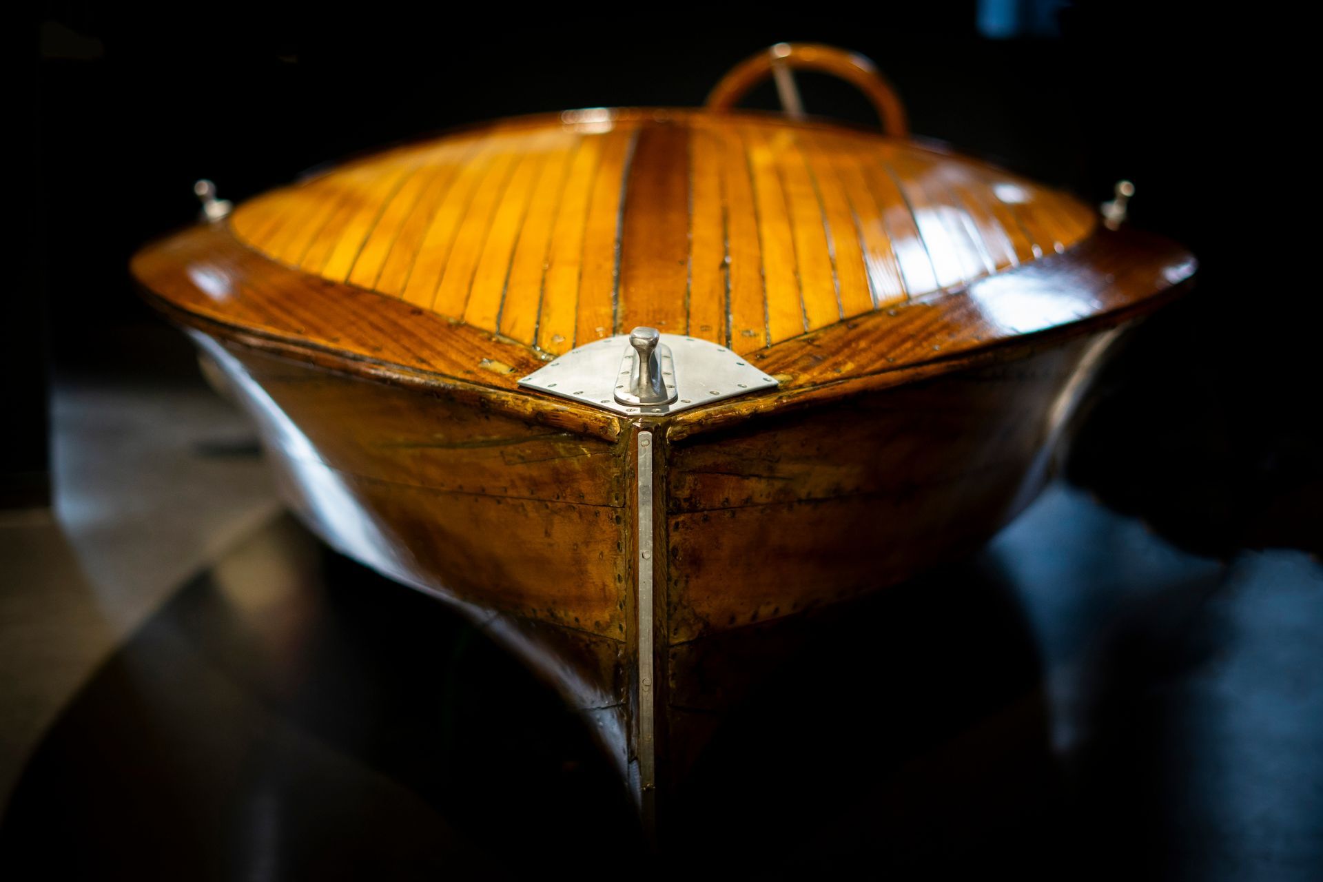 A wooden boat is sitting on a table in a dark room.