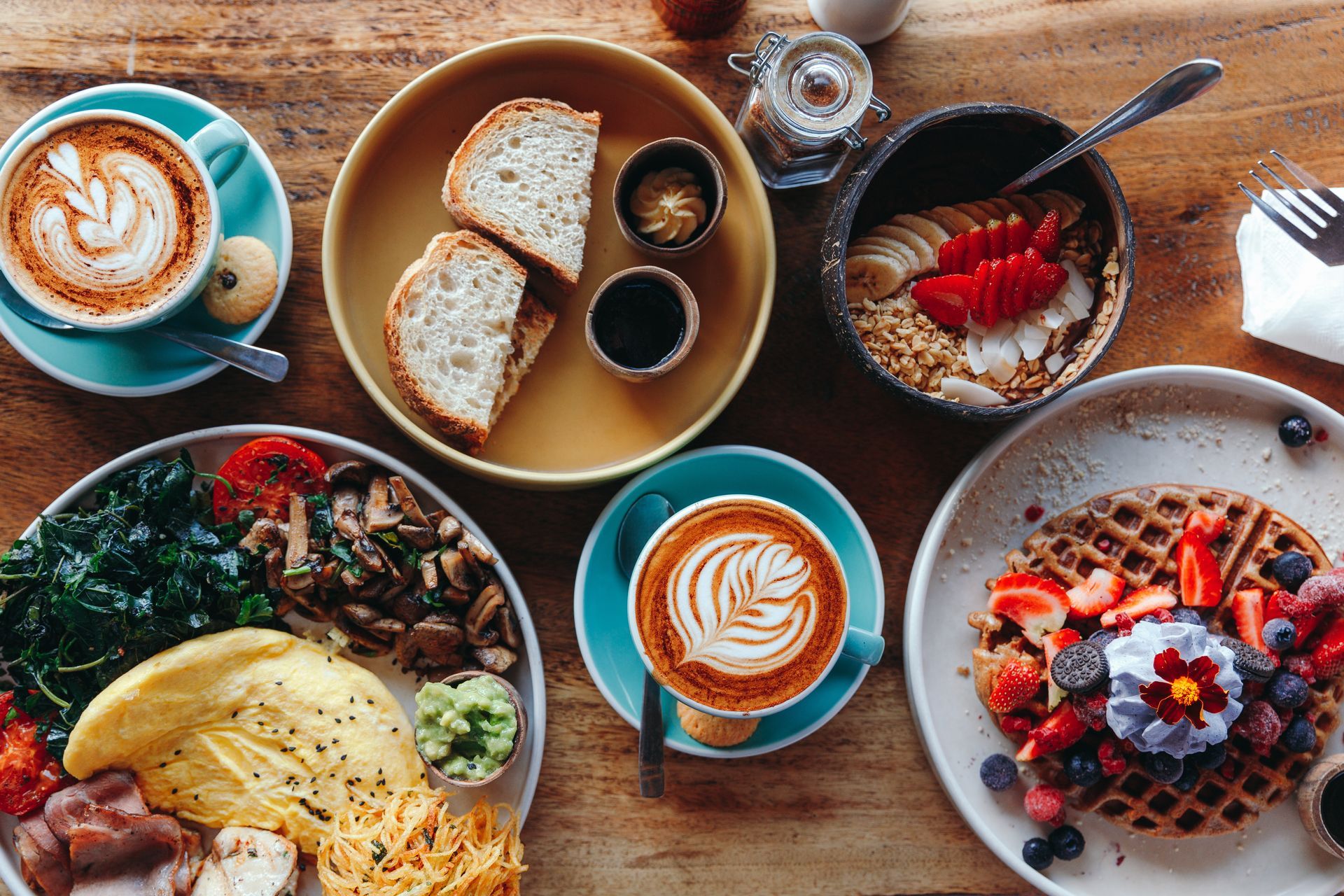 A table topped with plates of food and coffee cups.