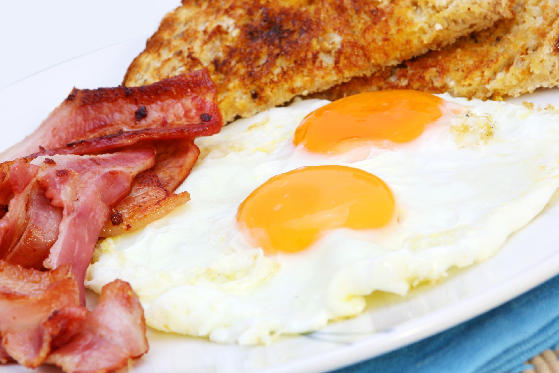 A white plate topped with eggs , bacon and toast.