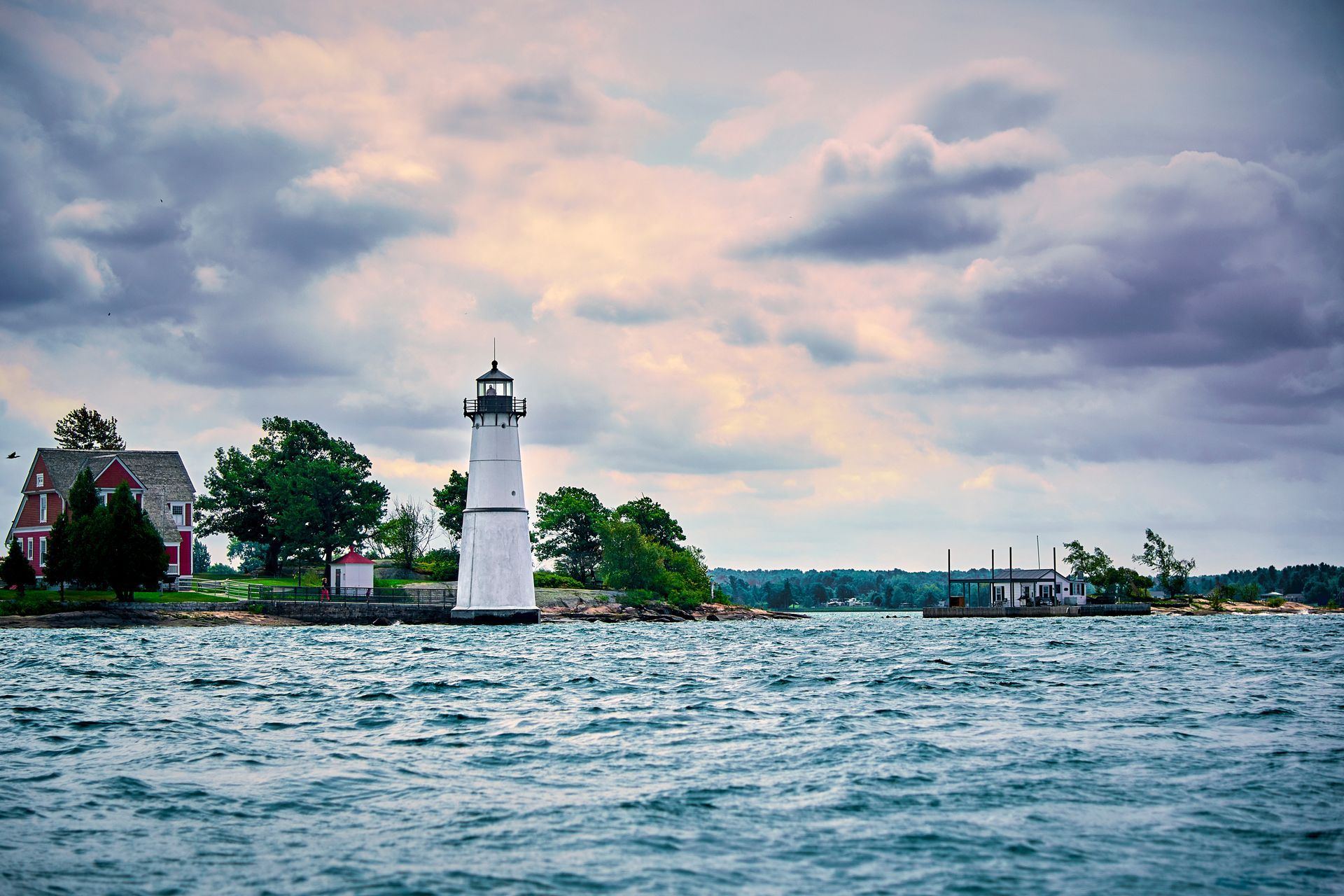 A lighthouse is sitting on top of a small island in the middle of a body of water.