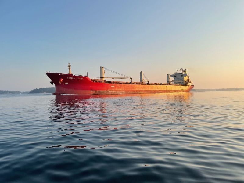 A blue boat is floating on top of a large body of water.