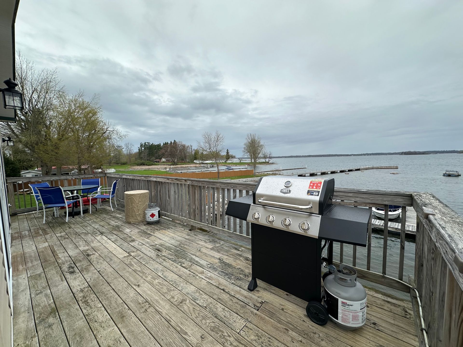A grill is sitting on a wooden deck overlooking a body of water.