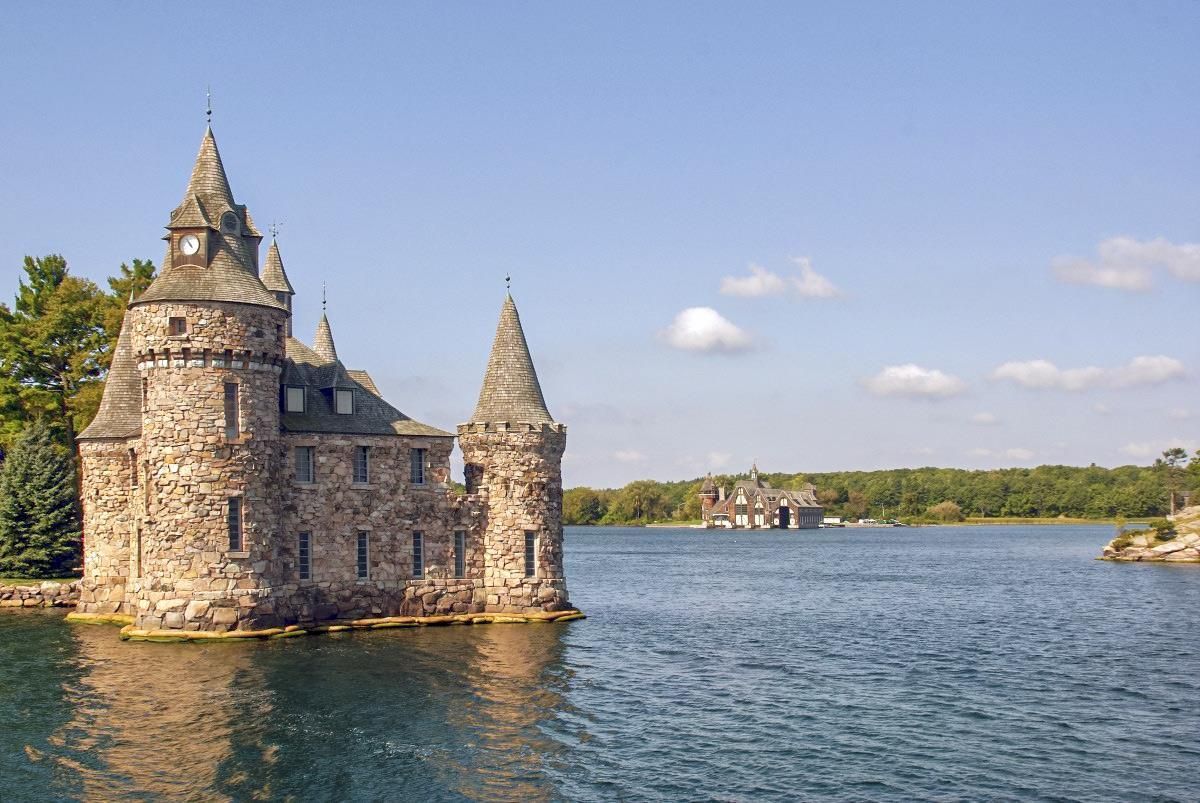 A castle is sitting on top of a small island in the middle of a lake.