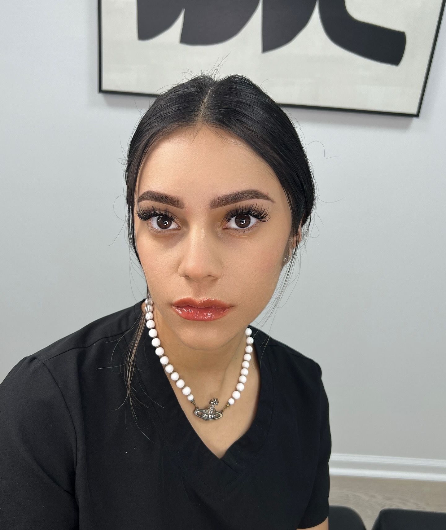 A woman wearing a black shirt and a pearl necklace