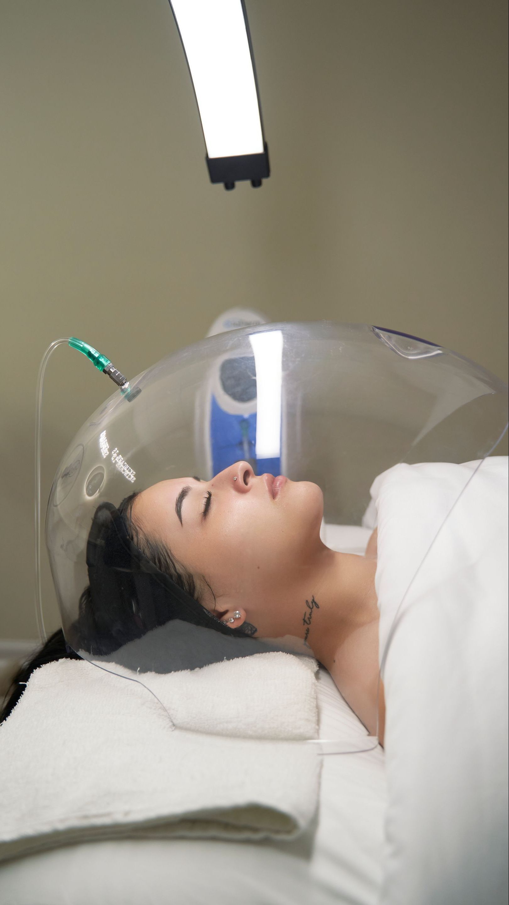 A woman is laying on a bed with a clear dome over her head.