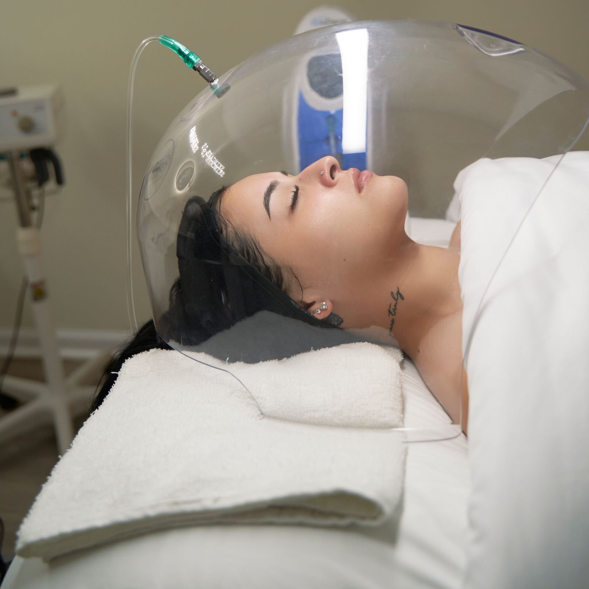 A woman is laying on a bed with a clear dome over her head.