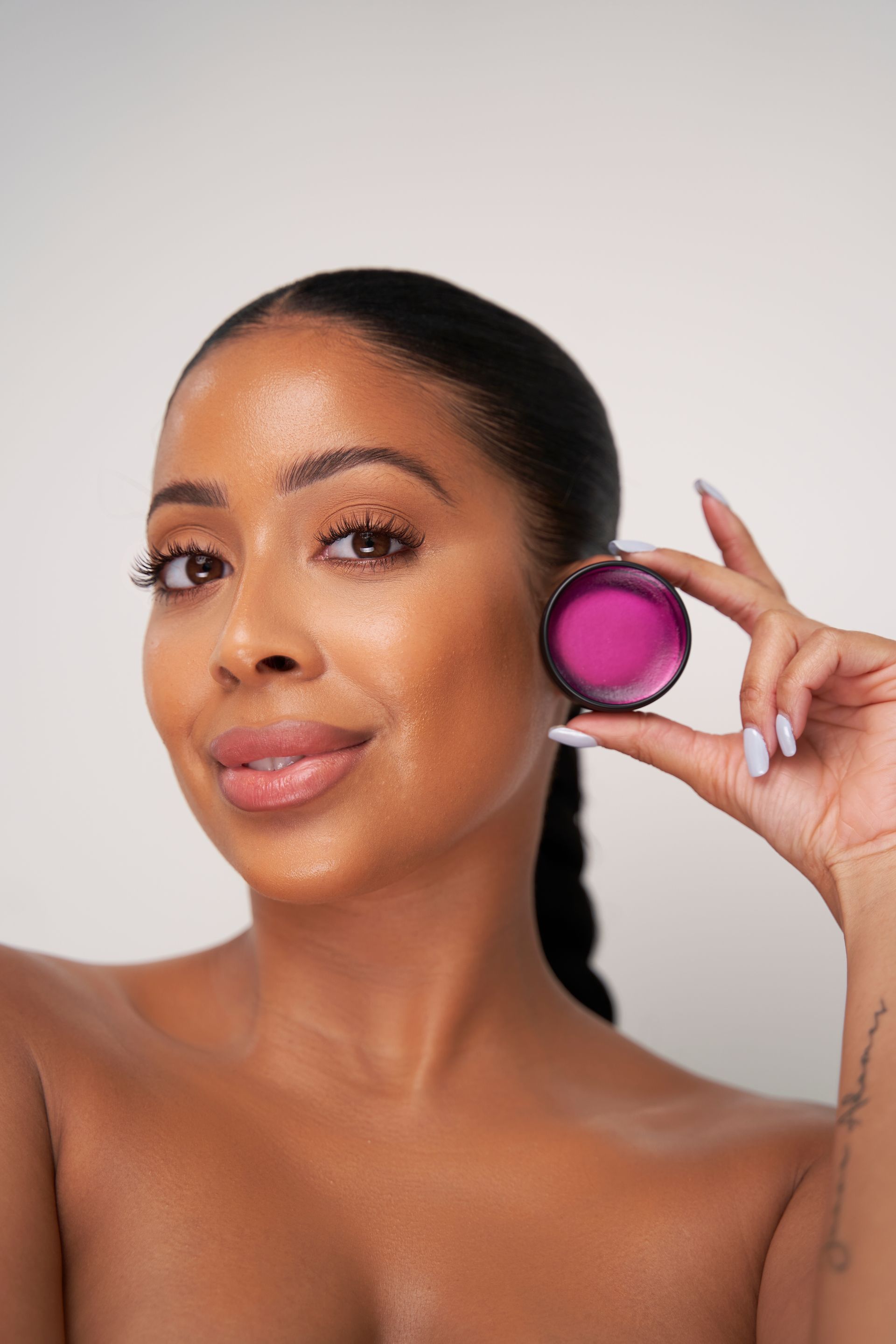 A woman is holding a pink object in front of her face.