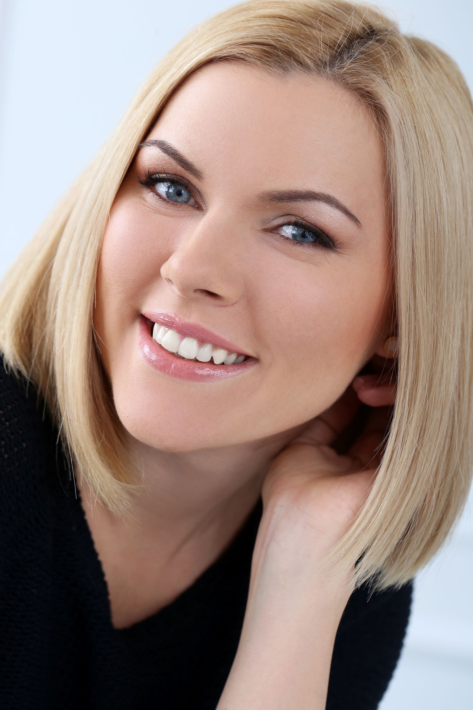 A woman with blonde hair and blue eyes is smiling for the camera.