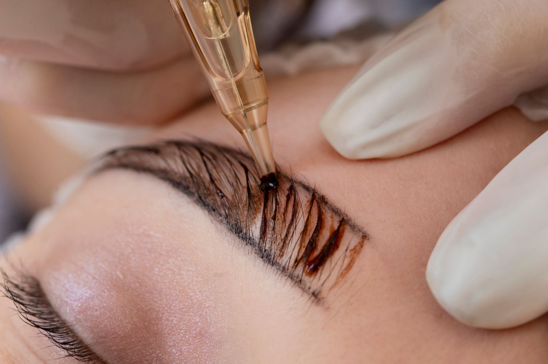 A woman is getting permanent makeup on her eyebrows.