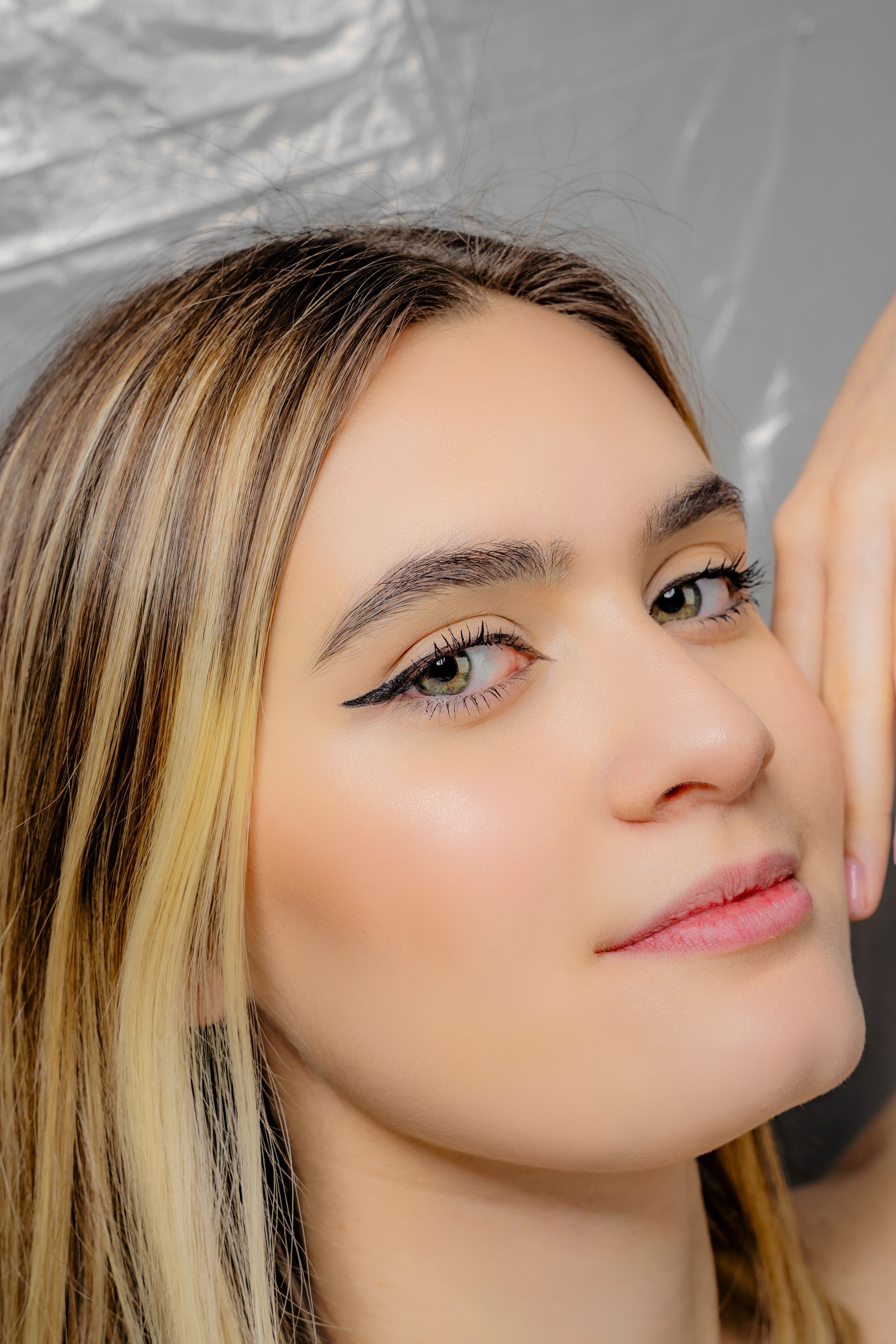 A close up of a woman 's face with her hand on her face.