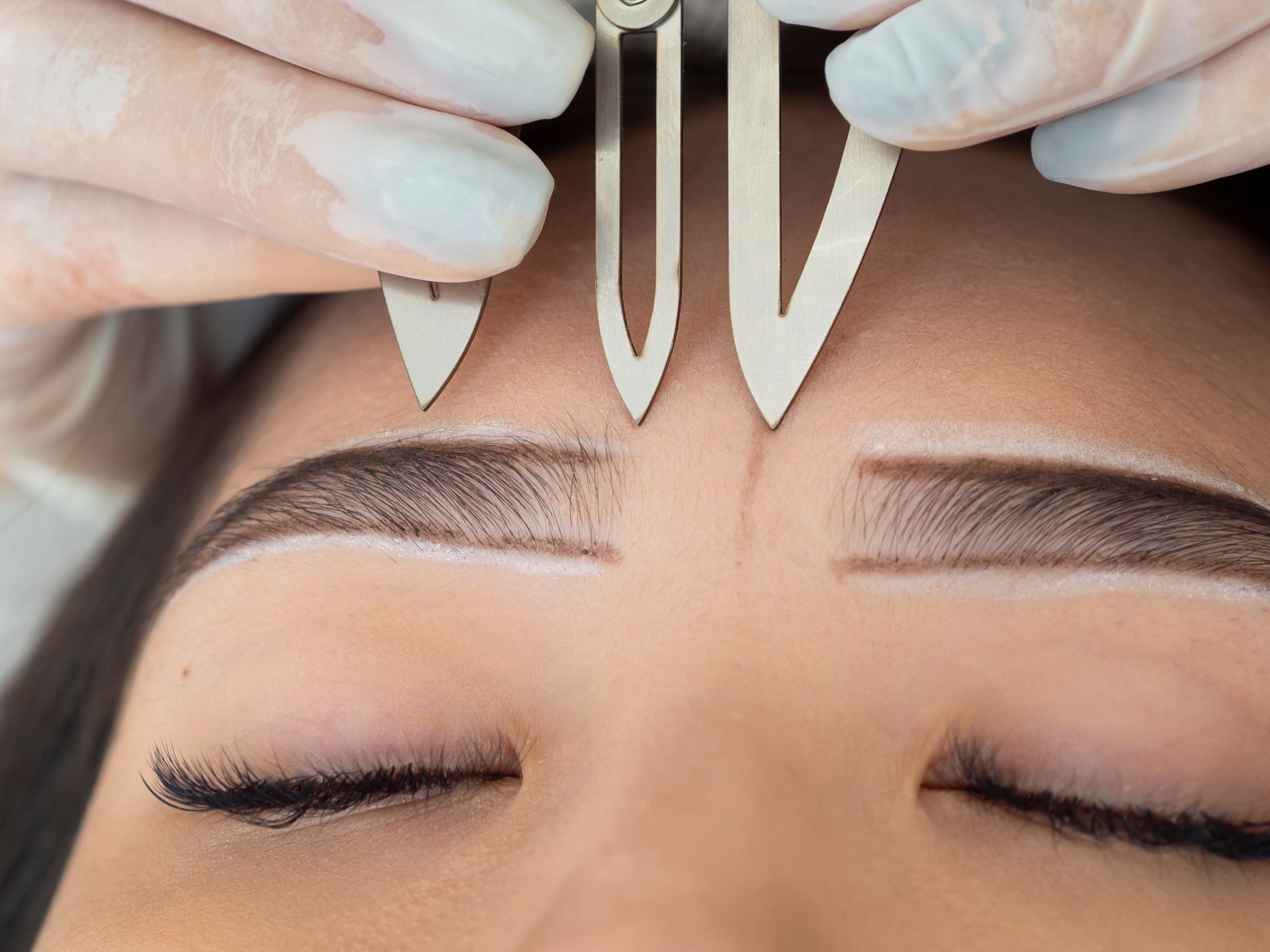 A woman is getting a permanent makeup tattoo on her eyebrows.