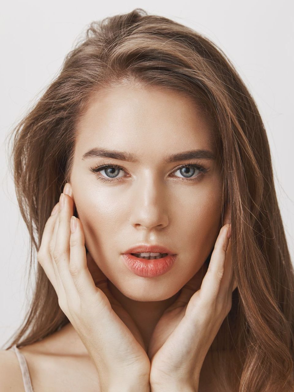 A close up of a woman 's face with her hands on her face