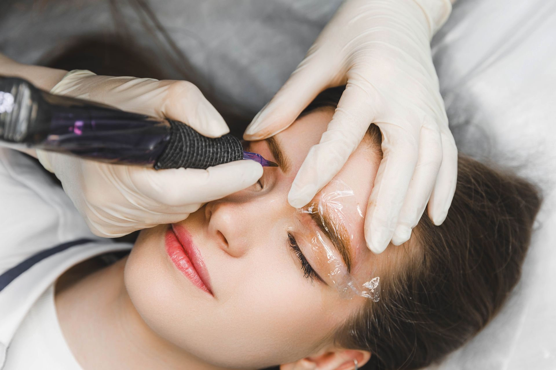 a woman getting eyebrow tattoo